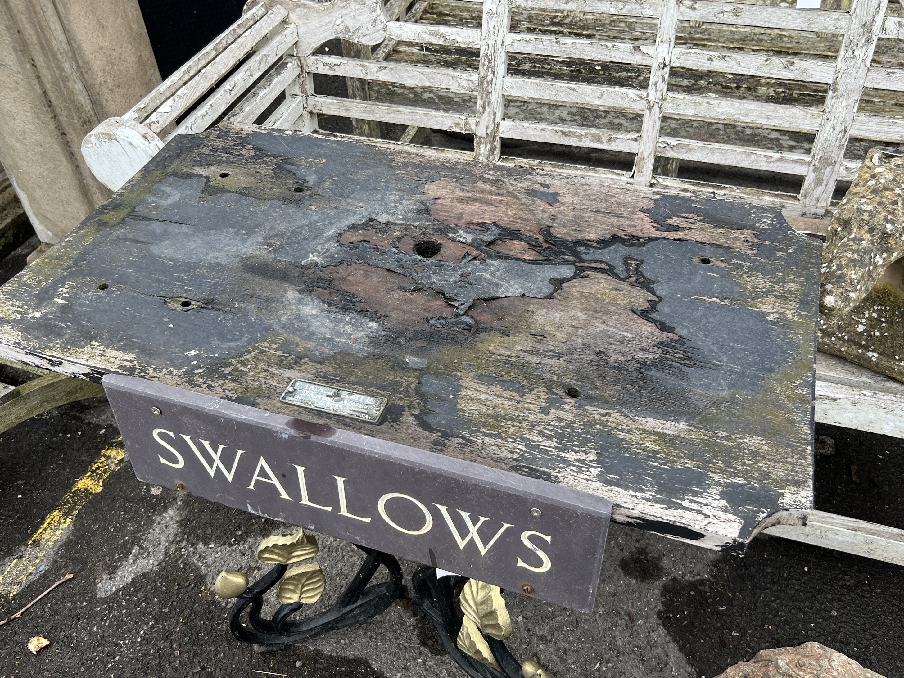 A rectangular cast iron and weathered teak garden table with a sign reading 'Swallows', width 91cm, depth 53cm, height 71cm